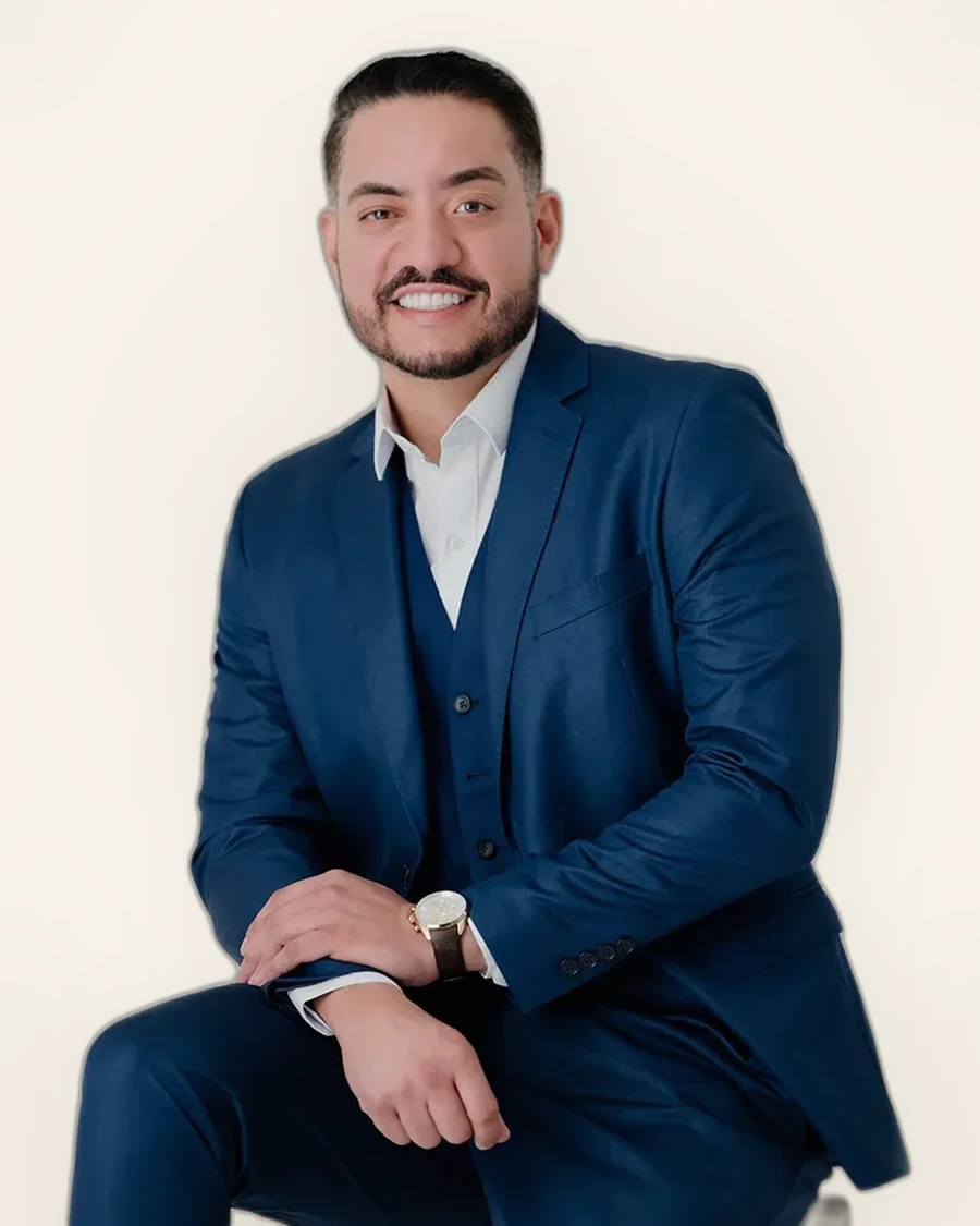 Dr. Marco Antônio sentado em poltrona, terno claro, sorrindo